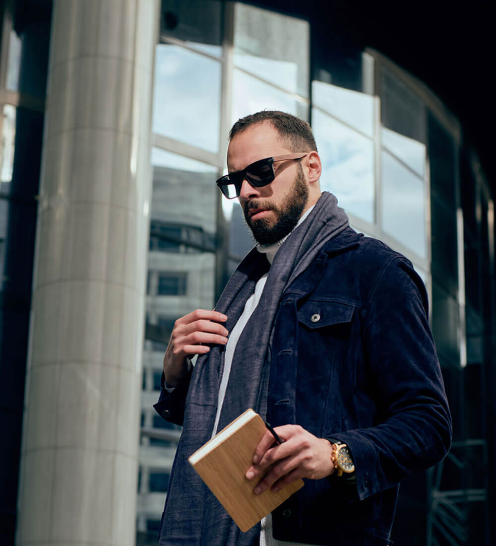 a man wearing sunglasses and holding a notebook