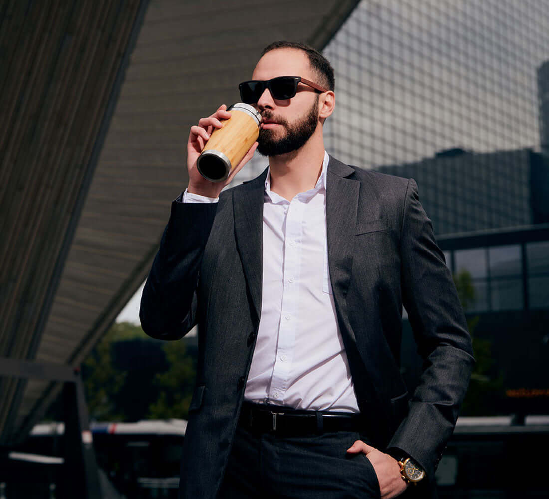 man in his formals sipping coffee from his bottle